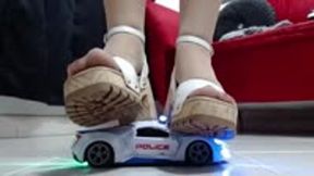 crushing a police toy car robot with nylons and hard soled wooden sandals