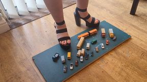 Giantess Lou in car park chaos, she crushes lots of little cars vans trucks and buses in big black chucky heels high left view